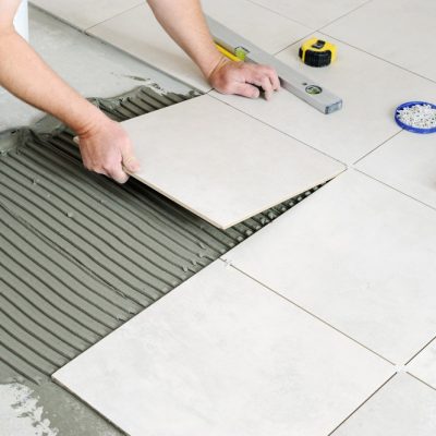 hands-worker-are-laying-ceramic-tile-floor